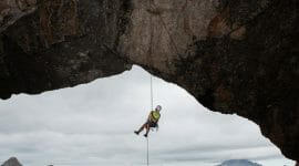 Abseiling Man down to the snow on a rocky hill